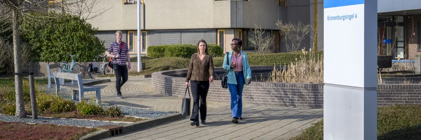 Mensen lopen over de stoep langs een kantoorgebouw